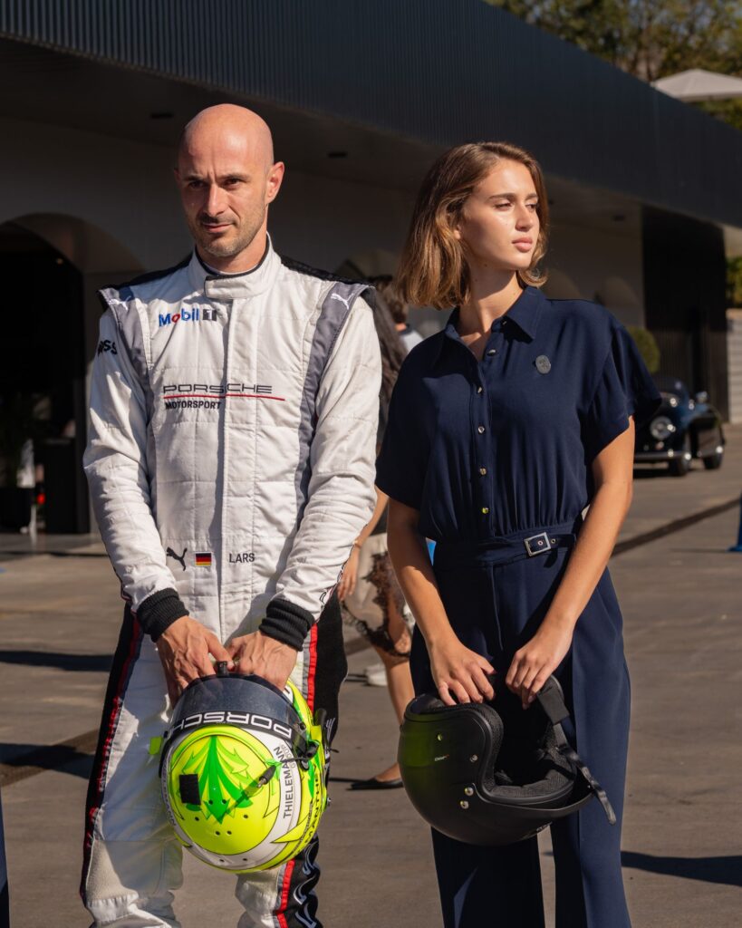 Racing driver and model holding helmets at a racing club fashion campaign